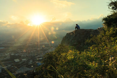 Man sitting on cliff at sunset