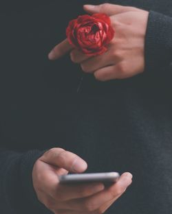 Close-up of hand holding smart phone over black background