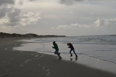 Men and women on beach against sky