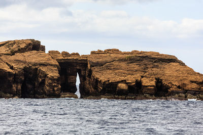 Rock formations by sea against sky