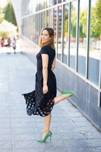 Portrait of smiling woman standing on footpath