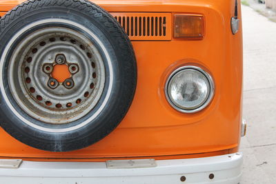 Close-up on the front of an orange volkswagen combi with its spare wheel.