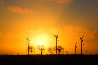 Low angle view of electricity pylon against sky during sunset