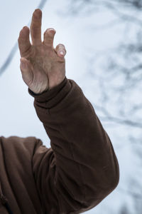 Close-up of man hand against sky