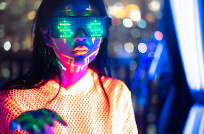 Portrait of woman standing against illuminated lights