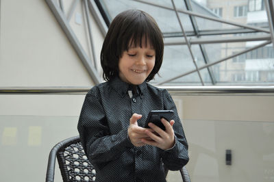 Caucasian schoolerboy using modern technology and video chatting with friends mobile in cafe