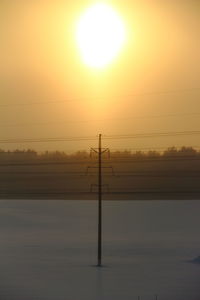 Silhouette electricity pylon against sky during sunset