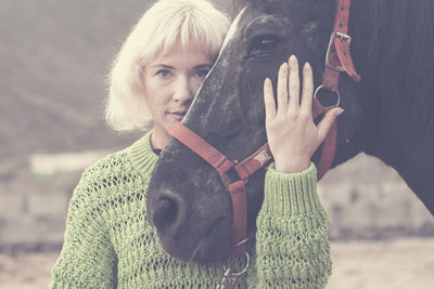 Portrait of woman standing with horse in winter