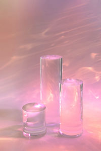 Three clear glass cylinder podiums on pastel pink background