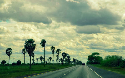 Country road against cloudy sky