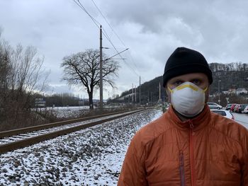 Portrait of man standing on railroad track during winter
