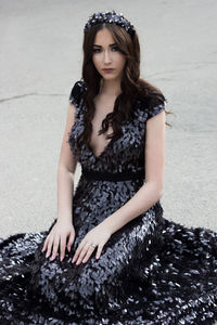 Portrait of beautiful woman wearing black evening gown while kneeling on road