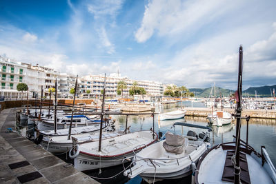 Sailboats moored at harbor in city against sky