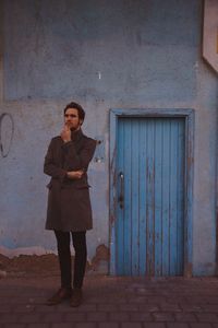 Full length portrait of woman standing against building