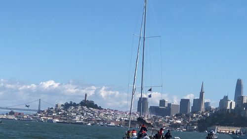 Sailboats in sea by buildings against sky in city