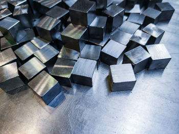 Pile of small machined shiny steel cubes on metal surface