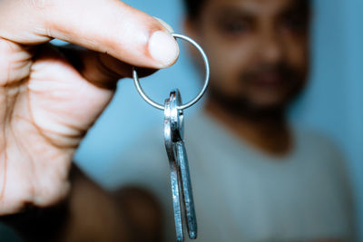 Close-up of man holding key standing against wall