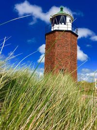 Lighthouse on field against sky