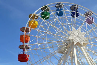 Low angle view of ferris wheel against blue sky