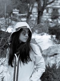 Portrait of young woman standing on snow covered tree