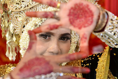 Close-up portrait of bride showing henna tattoos on hands during wedding ceremony