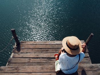 Rear view of man sitting on jetty