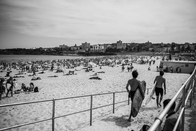 People at beach against sky in city