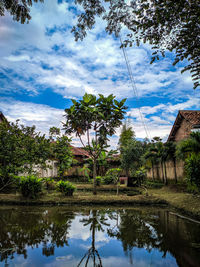 Reflection of trees and buildings in lake against sky