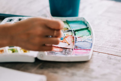 Close-up of woman's hand mixing watercolors with brush