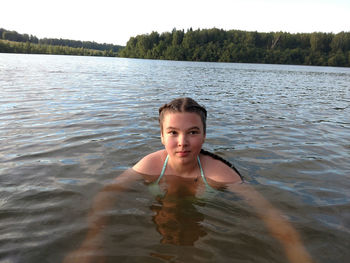 Portrait of beautiful young woman against lake