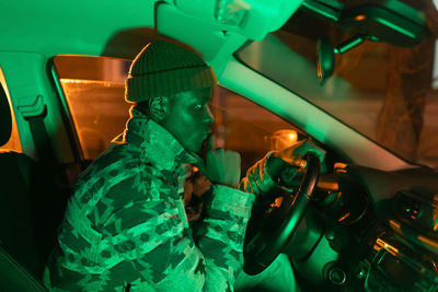 Depressed african man sit in car in darkness think about breakup with girlfriend or problem at work