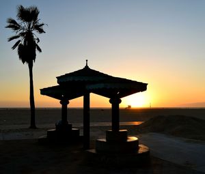 Silhouette of lifeguard hut on beach during sunset