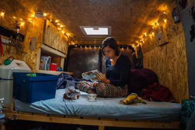 Woman reading newspaper while sitting in travel trailer