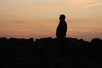 Silhouette man standing against orange sky