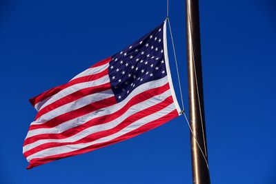 Low angle view of american flag against clear blue sky