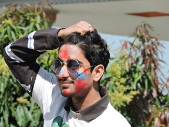 High angle view of young man with powder paint on face wearing sunglasses in park