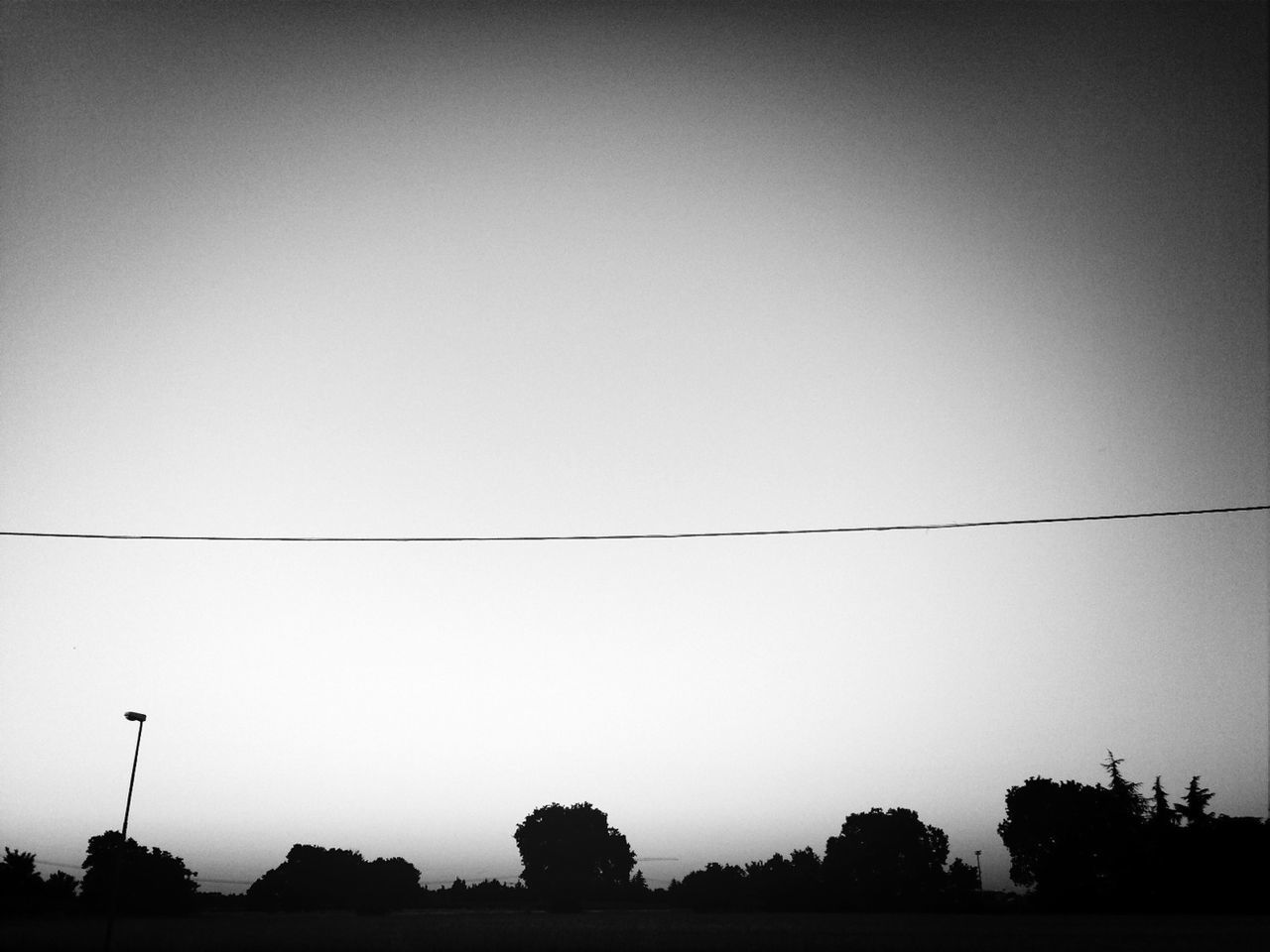 silhouette, copy space, tree, clear sky, tranquility, power line, tranquil scene, nature, sky, low angle view, beauty in nature, dusk, scenics, outdoors, electricity pylon, electricity, no people, connection, cable, street light