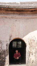 Portrait of man crouching on arch window