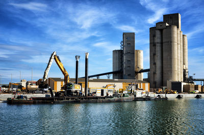 Cranes at harbor against sky