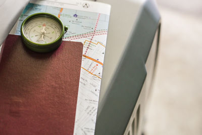 High angle view of navigational compass and passport on luggage