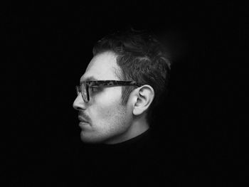 Close-up of man wearing eyeglasses against black background
