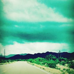 Country road against cloudy sky