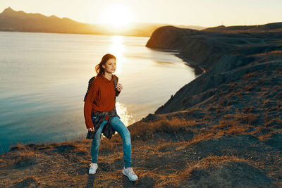 Full length portrait of man in sea against sky during sunset