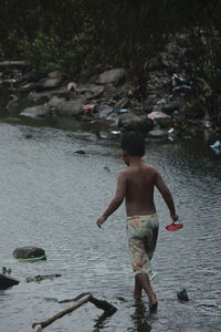 Rear view of shirtless boy at beach