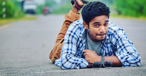 Portrait of young man lying on road