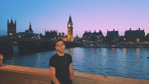 Young man looking at river with city in background