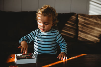 Full length of boy sitting on table at home