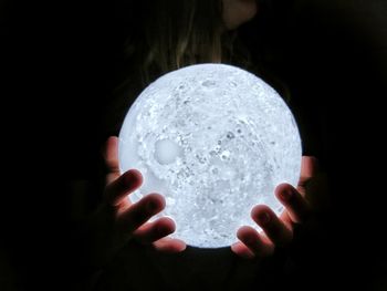 Close-up of hand holding ball against black background