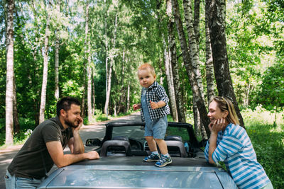 Mom, dad and little son in a convertible car. summer family road trip to nature