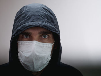 Portrait of man covering face against white background